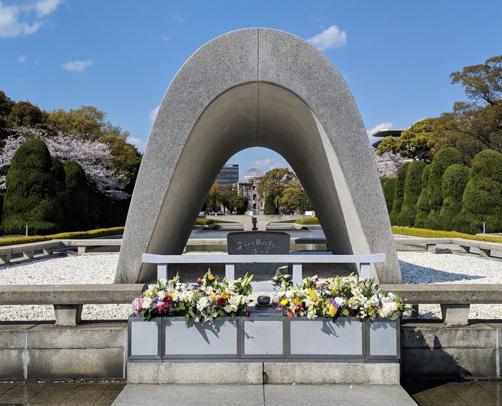 the cenotaph at Hiroshima Peace Memorial park with the atomic bomb dome seen in the background