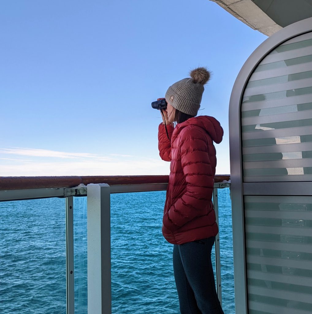 Gabi, The Fringe Explorer, looking out at the ocean with binoculars