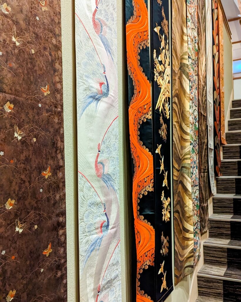 silk kimono obi with various designs hanging along the wall of a staircase