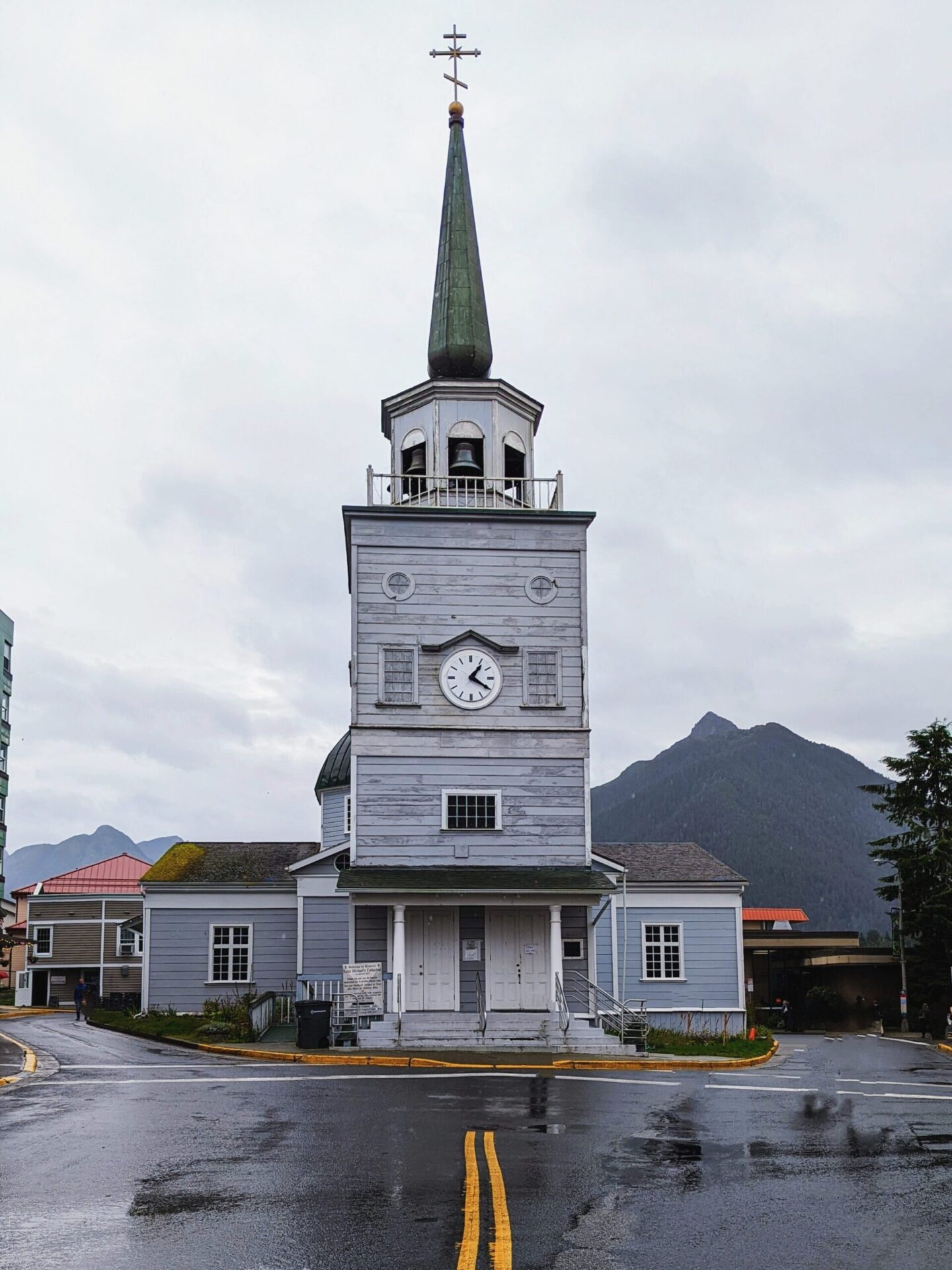 St. Michaels Orthodox Cathedral from the front. Old wooden style light blue grey panel church with a green spire