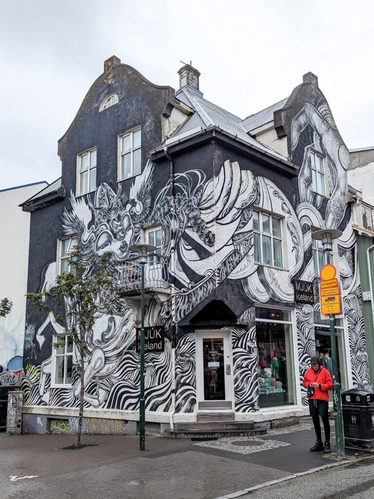 Photo of a house with a small shop on the ground floor. The outside of the house is fully decorated in black and white abstract art.