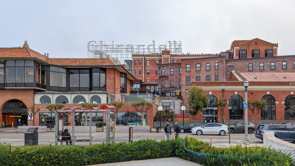 Old brick buildings with a scaffolding style sign on top that says "Ghirardelli"