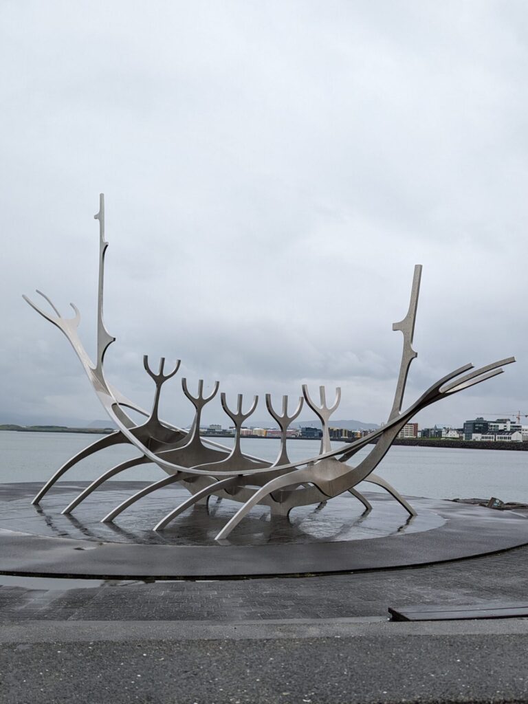 A Viking boat style metal sculpture at the edge of a bay