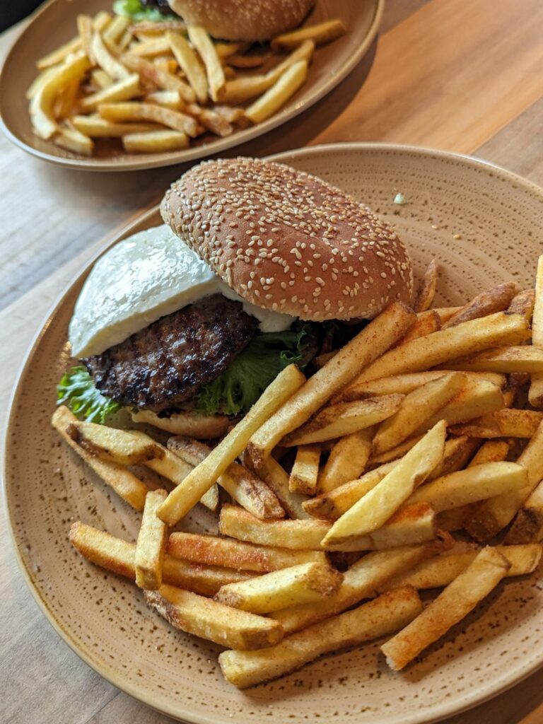 A tan plate with French fries and a burger