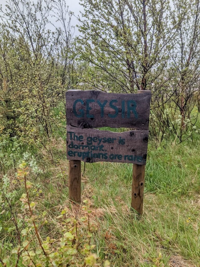 Wood sign at Geysir stating that the Geyser is dormant and eruptions are rate