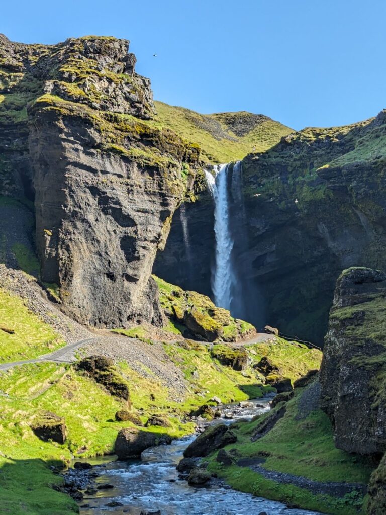 a waterfall cascading over a mossy rocky cliff inside a canyon.