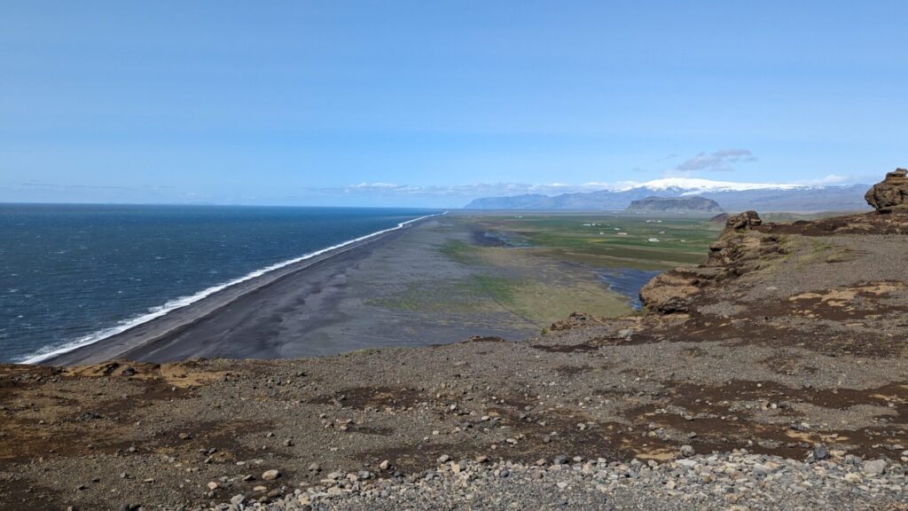 a sprawling black sand beach from a birds eye viewpoint