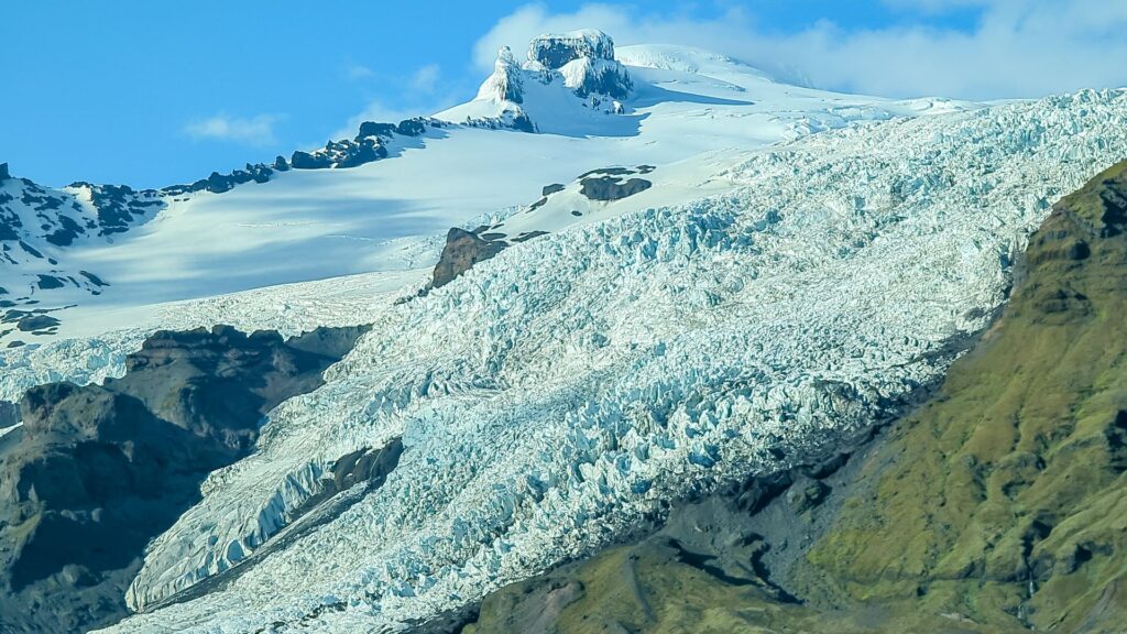 Zoomed in photo of a jagged blue and white glacier at the top of a snow mountain.