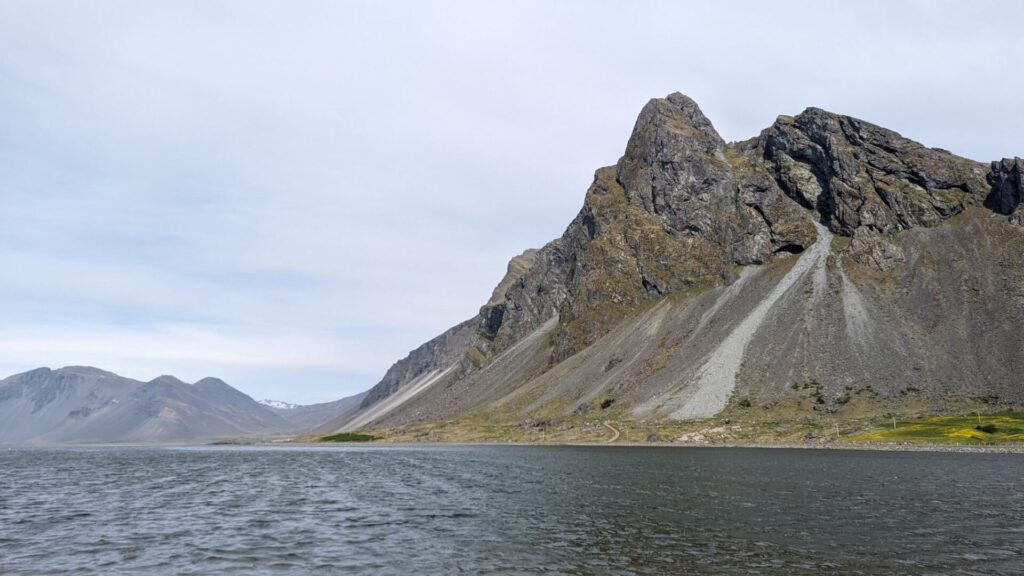 Looking out across a fjord at a jagged mountain.