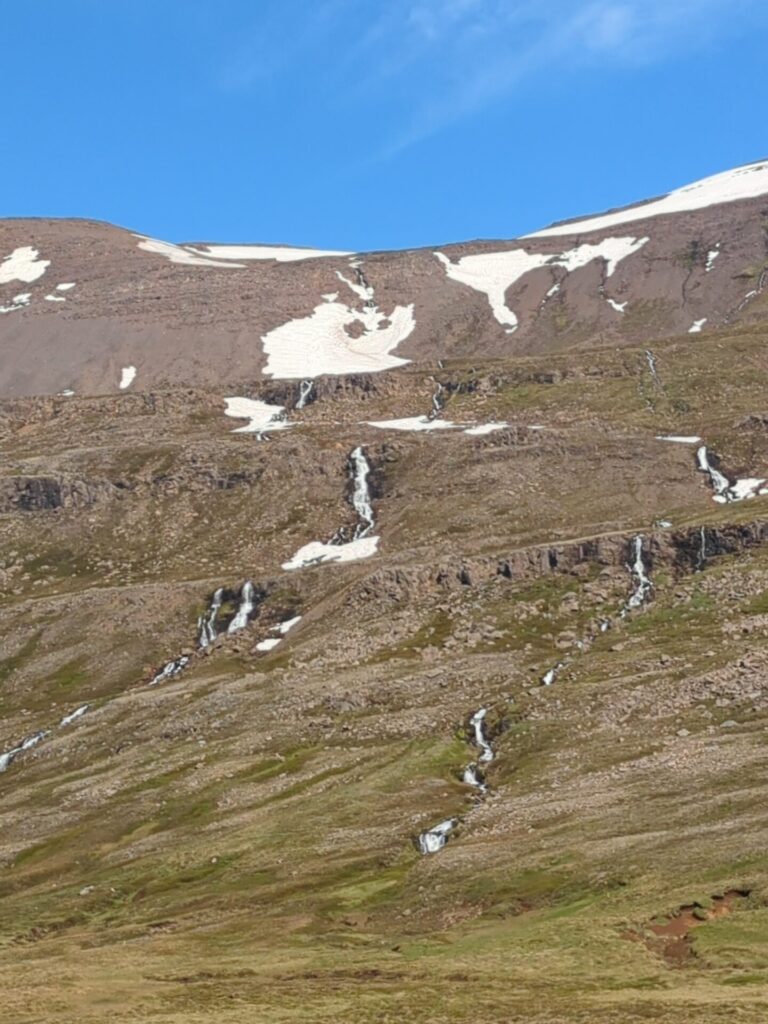 Narrow waterfalls cascading in multiple levels down a mountain side