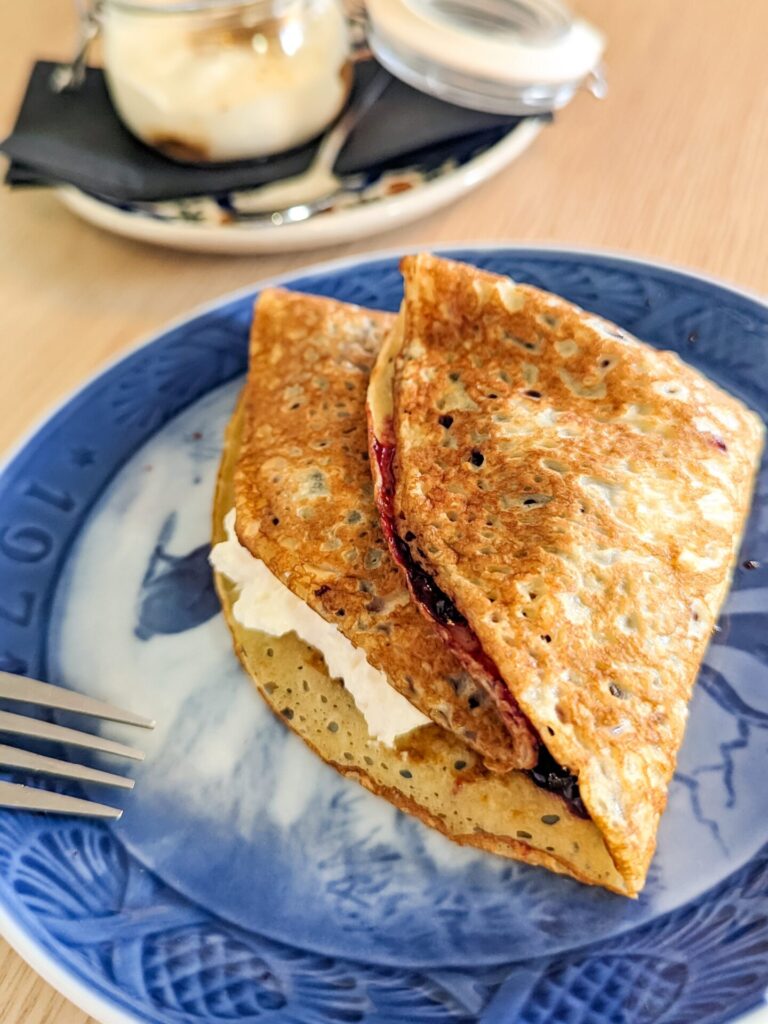 Icelandic pancake (like a crepe) with jam and cream inside sitting on a blue plate