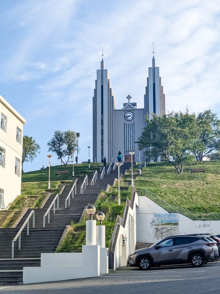 Large concrete church with two spires on top of a hill with multiple levels of stairs leading up to the front,