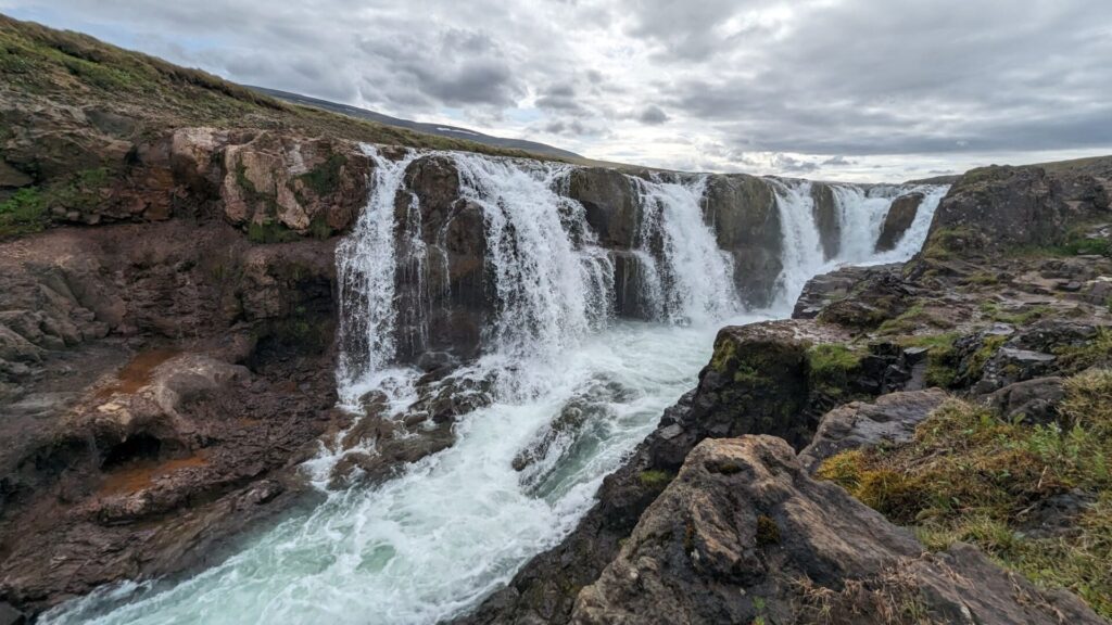 Multiple waterfall streams falling over a cliff into a canyon.