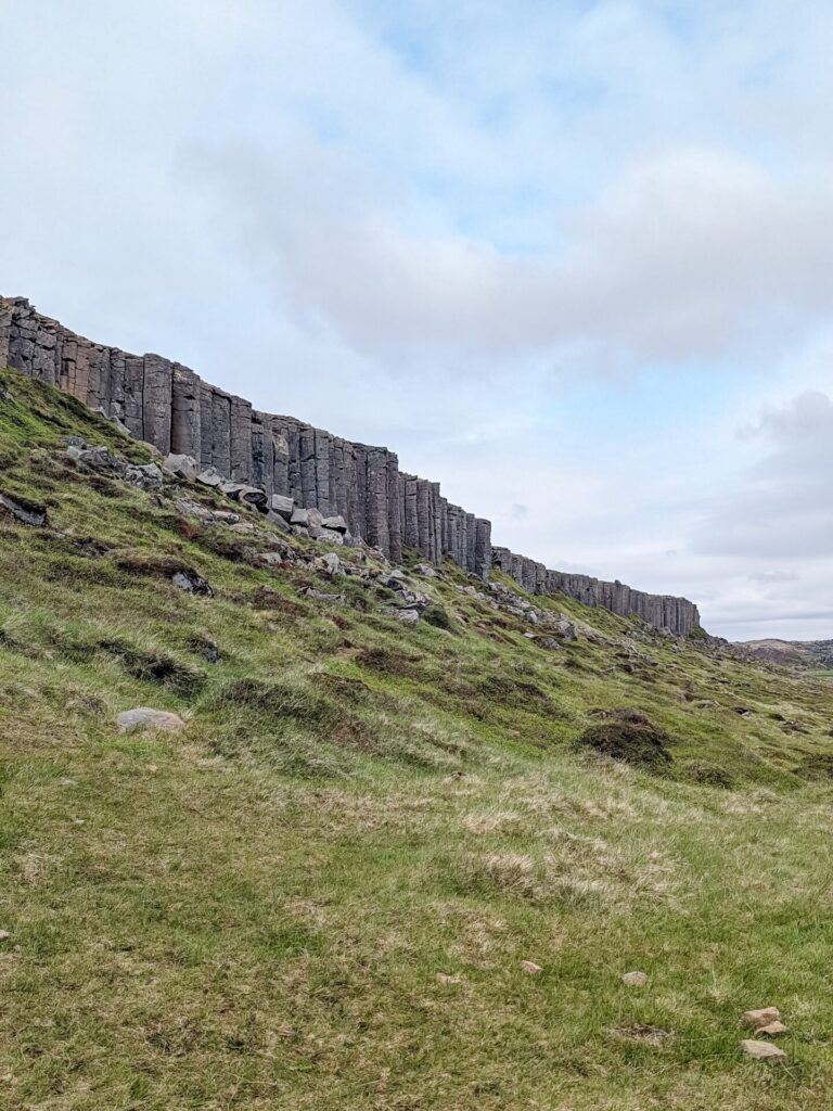 Looking at a basalt cliff at the top of a hill.