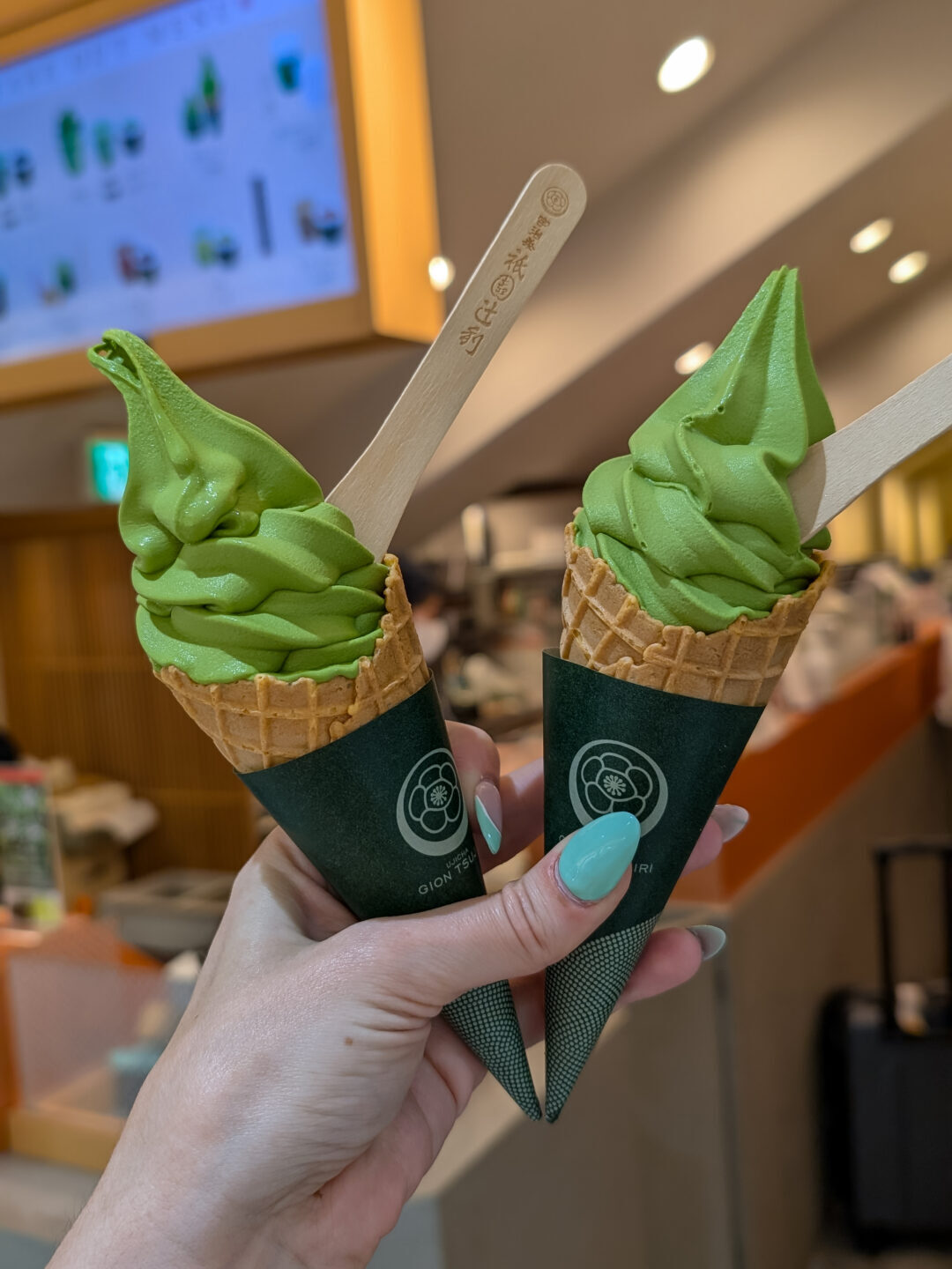 two matcha soft serve ice cream cones, the soft serve is bright green and has a bamboo spoon sticking out of it.