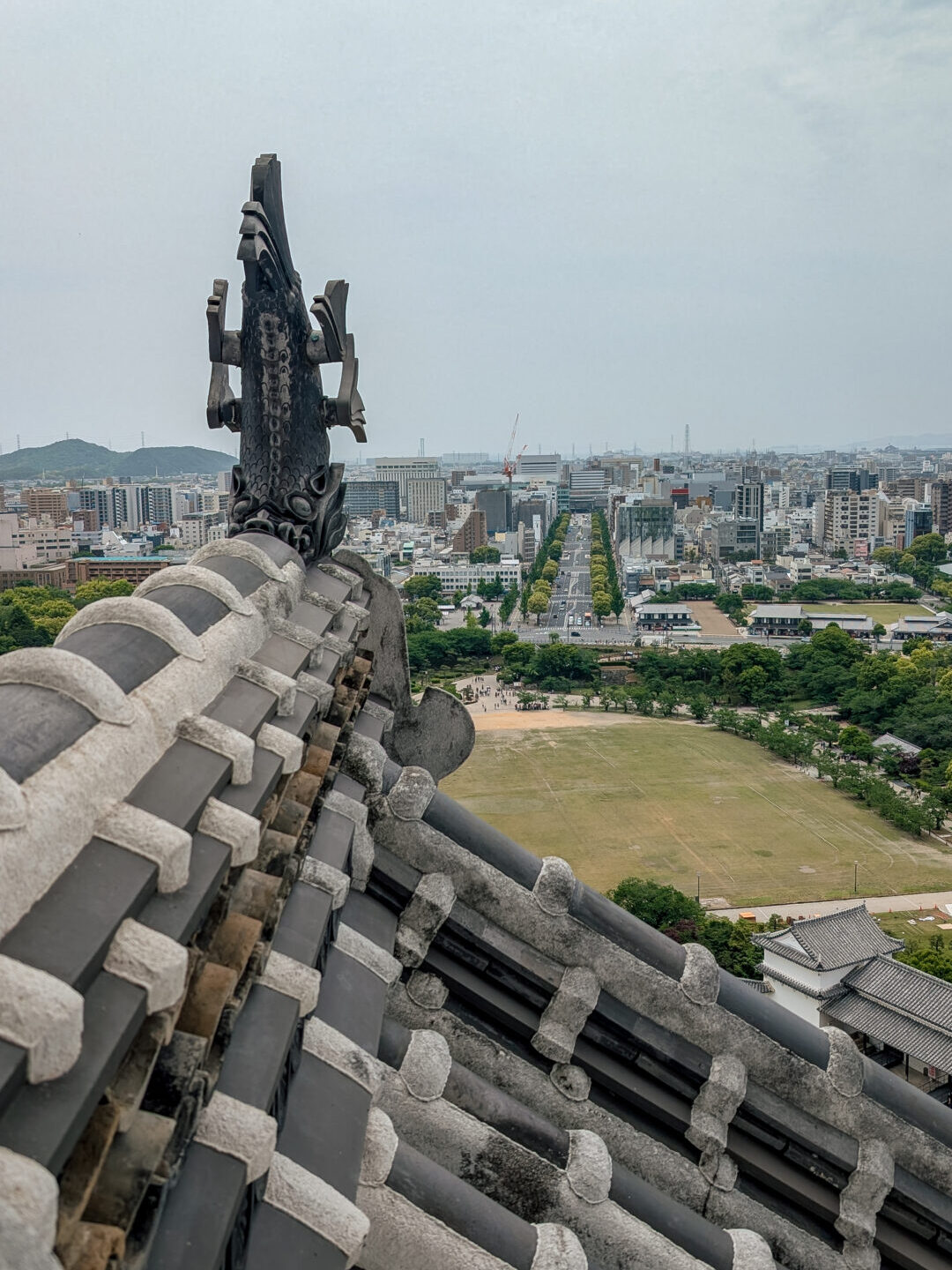 A view of a street outside of Himeji castle looking our over the roof of the castle from inside
