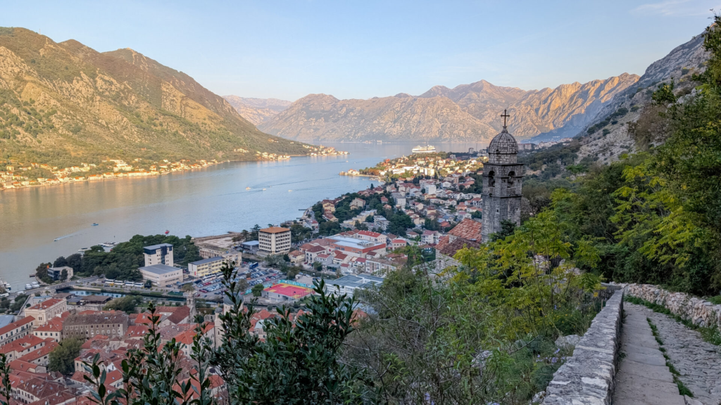 Scenic hiking path along the city walls overlooking the stone bell tower of the Church of Our Lady of Remedy and the Bay of Kotor.