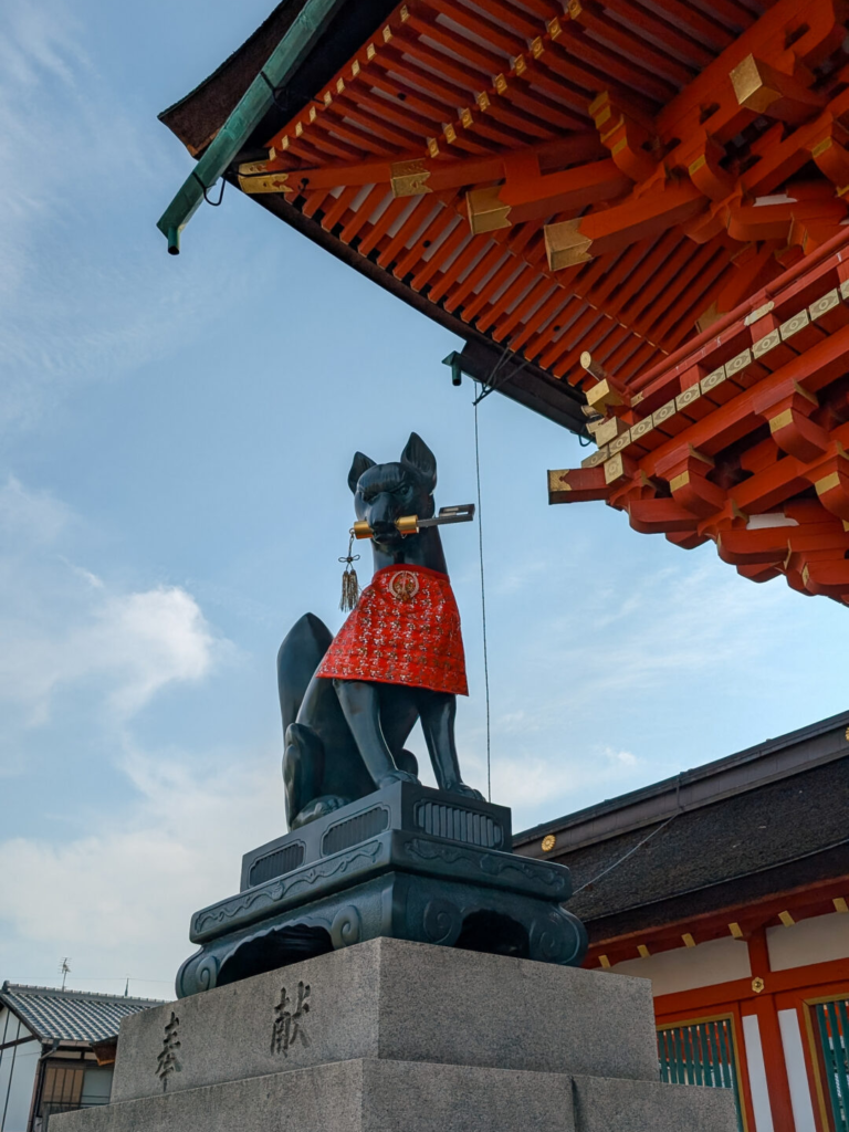 Bronze fox statue holding a key at the entrance of Fushimi Inari Taisha in Kyoto.