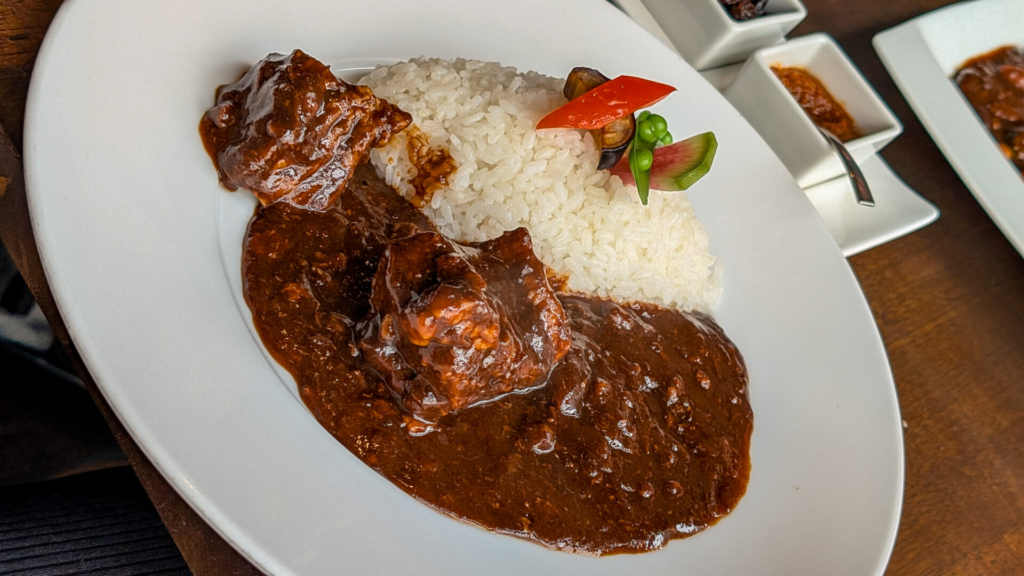 Rich Japanese beef curry with tender meat chunks served with white rice and fresh vegetable garnish at Nara Sanjo Curry.