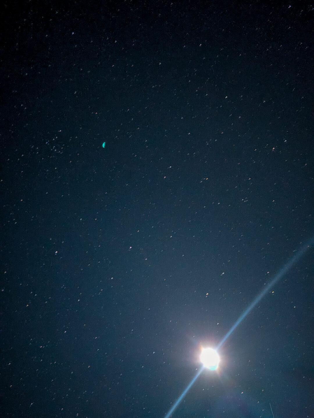 A stunning night sky view from Haleakala summit showing thousands of bright stars and a brilliant celestial body casting a long, bright lens flare across the dark sky.