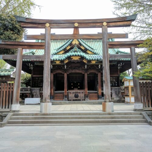 Ushijima Shrine in Sumida Park Tokyo. Shrine with a green roof and a wood tori gate in front of the shrine