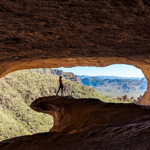 Gabi, The Fringe Explorer, standing on the natural stone wave at the entrance of the wave cave