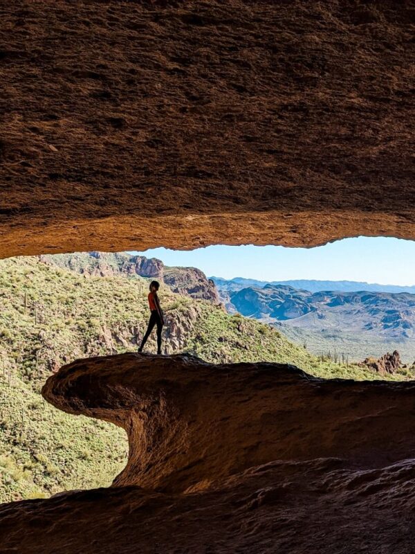 Gabi, The Fringe Explorer, standing on the natural stone wave at the entrance of the wave cave